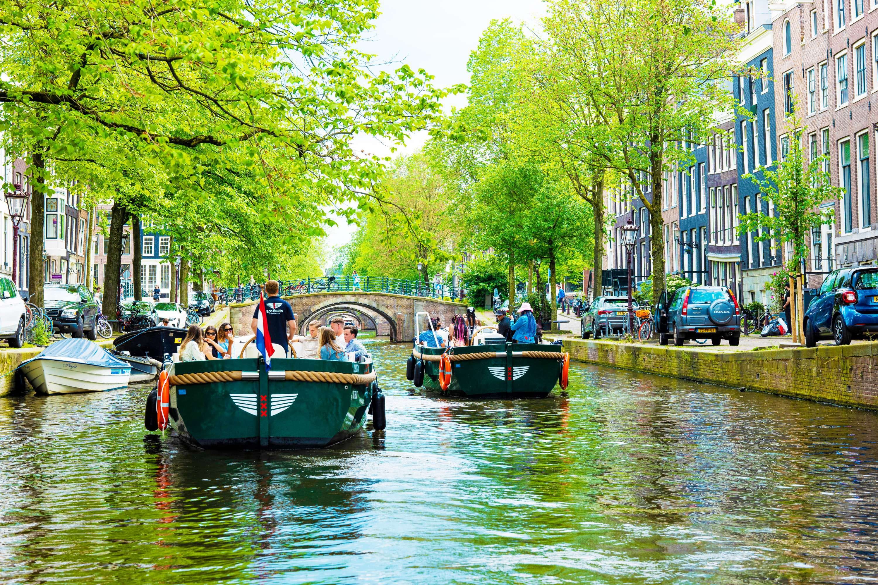 Privéboten varen op een groene Amsterdamse gracht tijdens een teamuitje